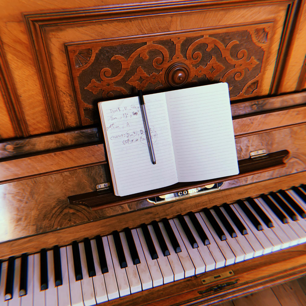 A piano with a notebook on the music rest.